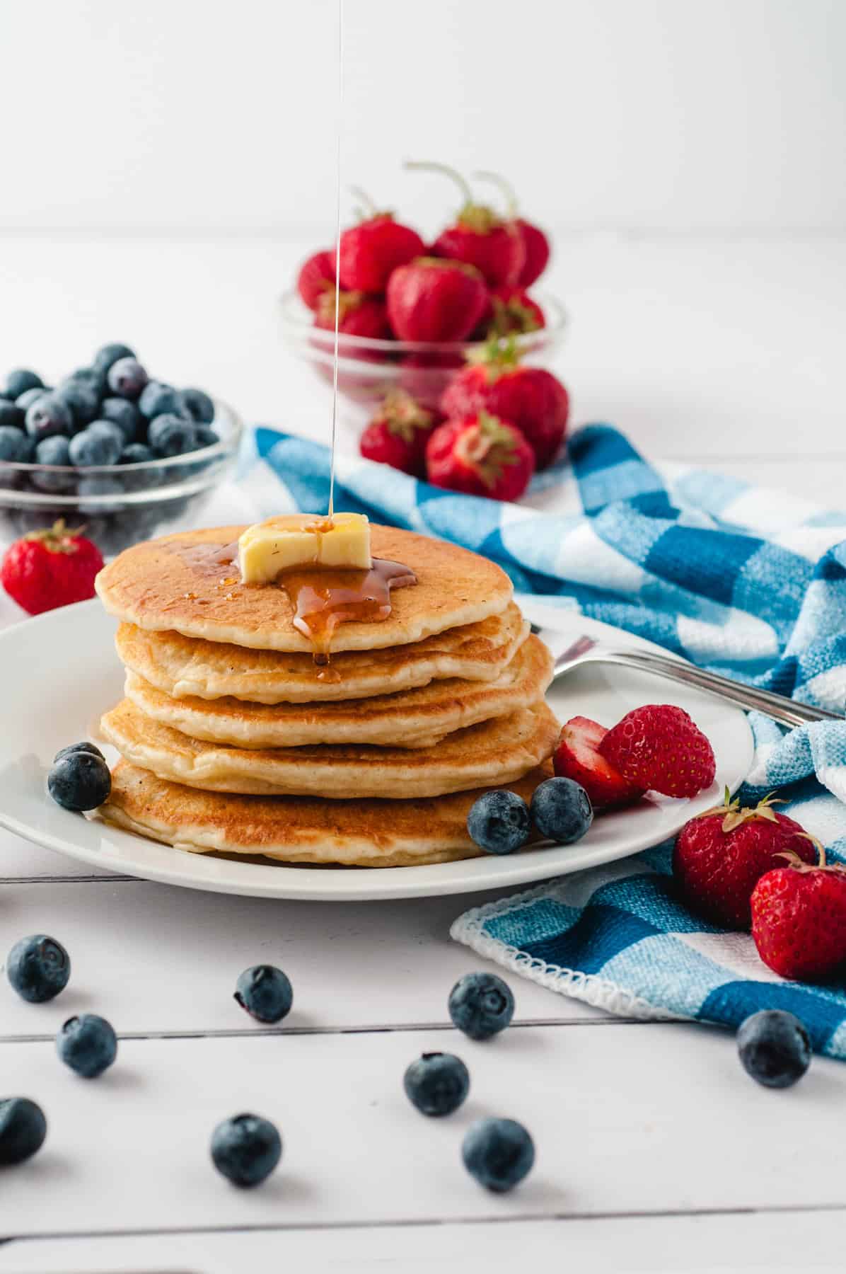 A stack of buttermilk pancakes on a plate with fruit