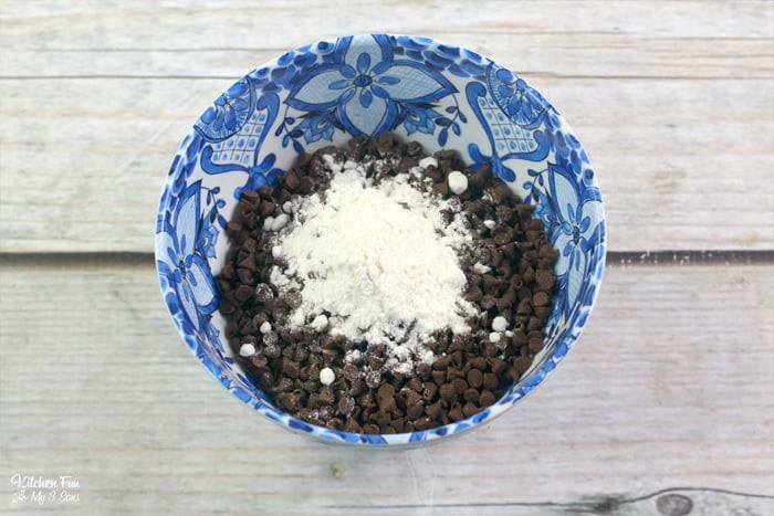 Chocolate chips and vanilla cake mix inside of a mixing bowl decorated with blue floral designs