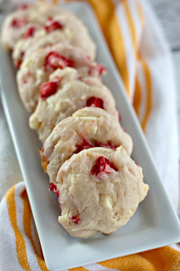 White chocolate strawberry cookies arranged in a row on a narrow platter.