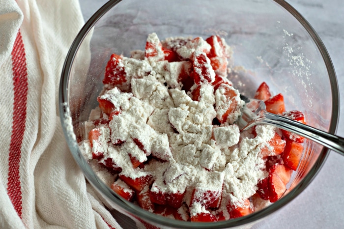Flour added to strawberries in a mixing bowl.