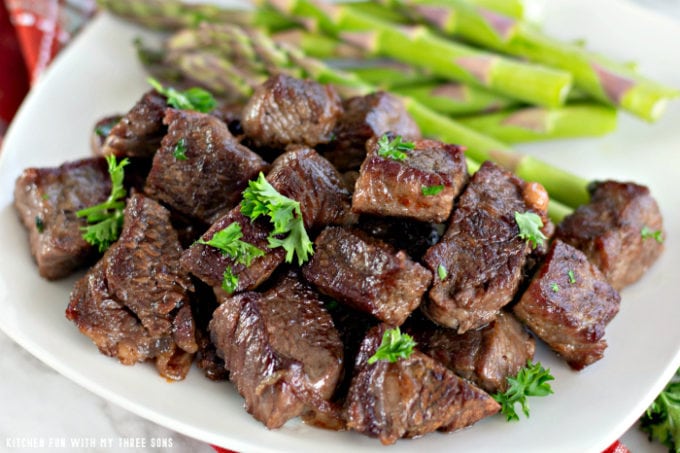 Garlic Butter Steak Bites on a white plate with steamed asparagus