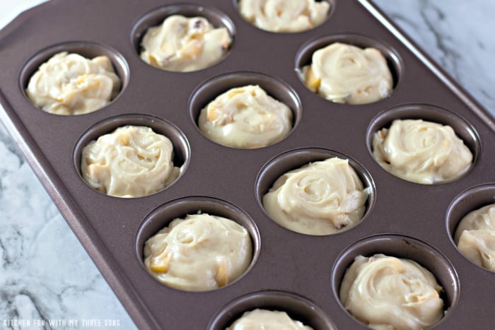 A twelve-count muffin tin full of the batter for mini peach upside down cakes