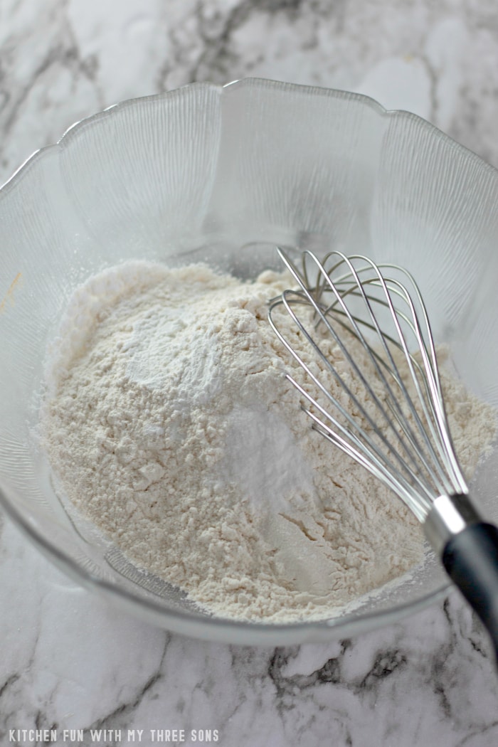 Flour, salt, baking powder and baking soda in a bowl with a metal whisk