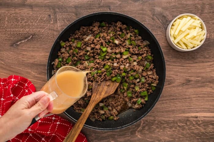 Philly Cheesesteak Sloppy Joes transform the cheesy goodness of a classic cheesesteak into a quick and easy sloppy joe in just 30 minutes. Pouring beef broth slurry into the ground beef mixture