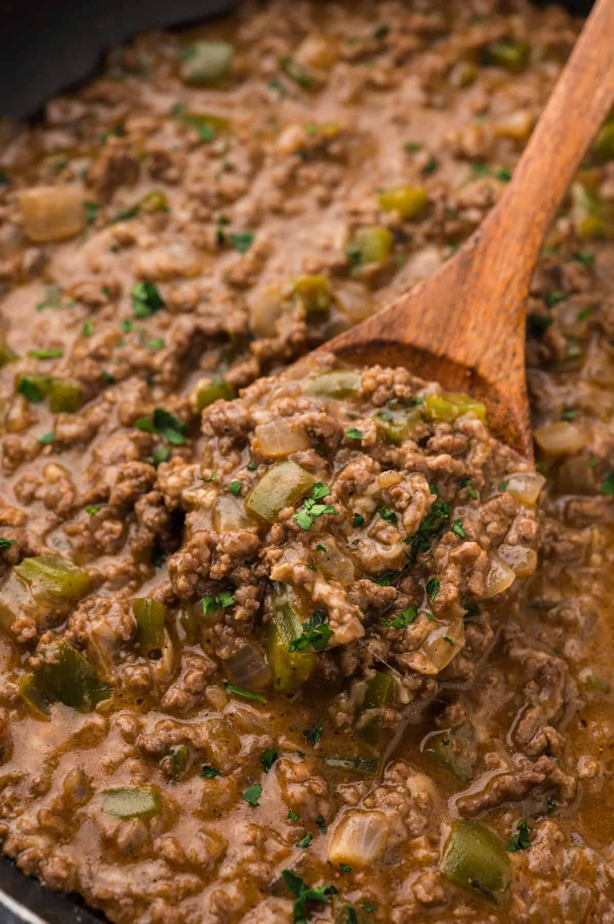 Philly Cheesesteak Sloppy Joes transform the cheesy goodness of a classic cheesesteak into a quick and easy sloppy joe in just 30 minutes. A wooden spoon stirring Philly cheesesteak sloppy joe filling