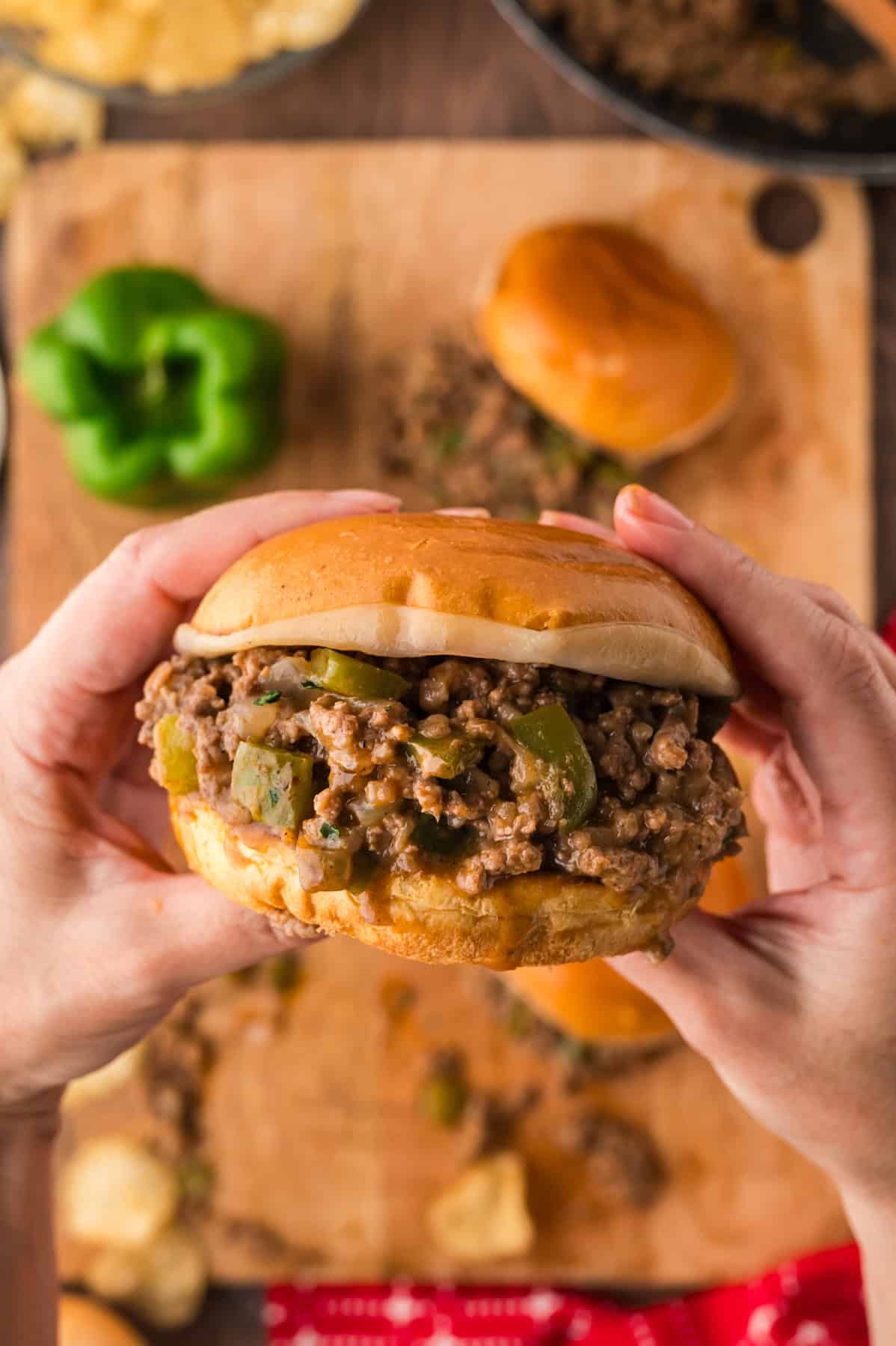 Philly Cheesesteak Sloppy Joes transform the cheesy goodness of a classic cheesesteak into a quick and easy sloppy joe in just 30 minutes. A hand holding a Philly cheesesteak sloppy joe