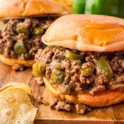 Two Philly cheesesteak sloppy joes on a wooden cutting board