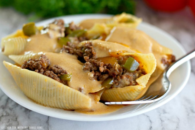 Philly Cheesesteak Stuffed Shells on a white plate with a fork on a marble countertop