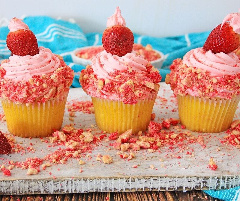 Three strawberry crunch cupcakes on a counter