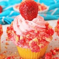 A strawberry crunch cupcake topped with a fresh strawberry