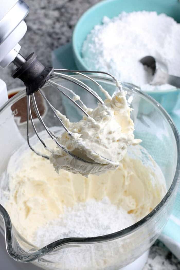 Thick and creamy with a delightfully tangy flavor, this Cream Cheese Frosting recipe requires just 4 basic ingredients and 15 minutes. whisking cream cheese frosting in a standing mixer