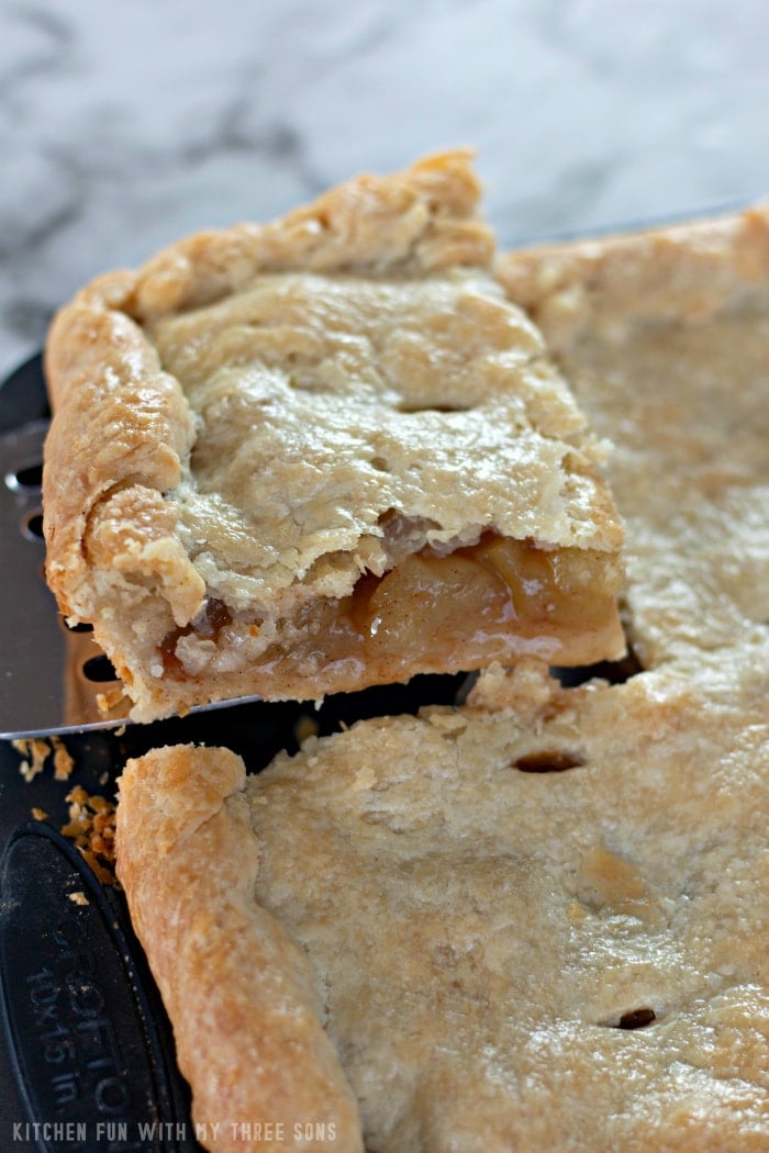 The corner of a double-crusted Apple Slab Pie, with a square being lifted out on a spatula.