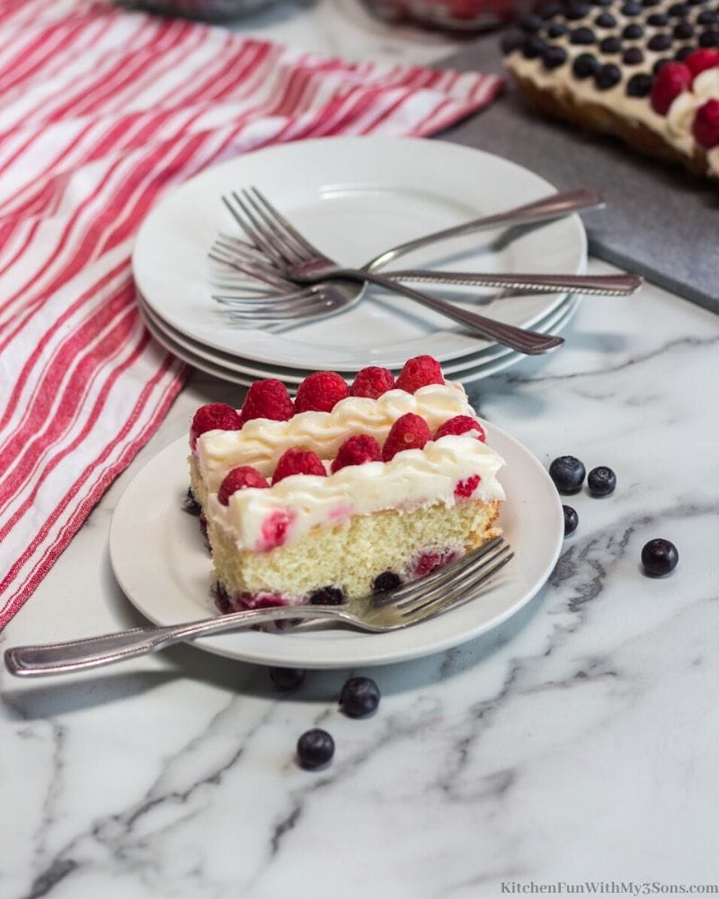 white cake with white frosting with blueberries and raspberries