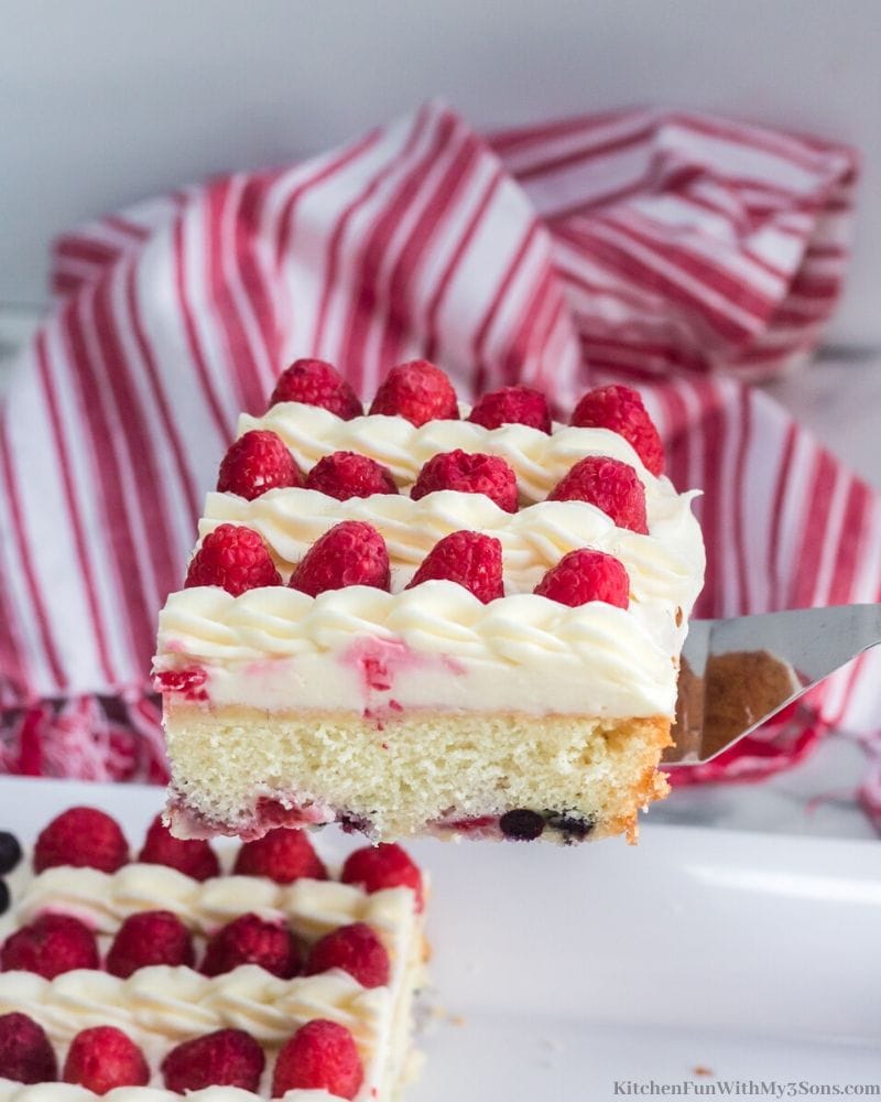 white cake with white frosting with blueberries and raspberries