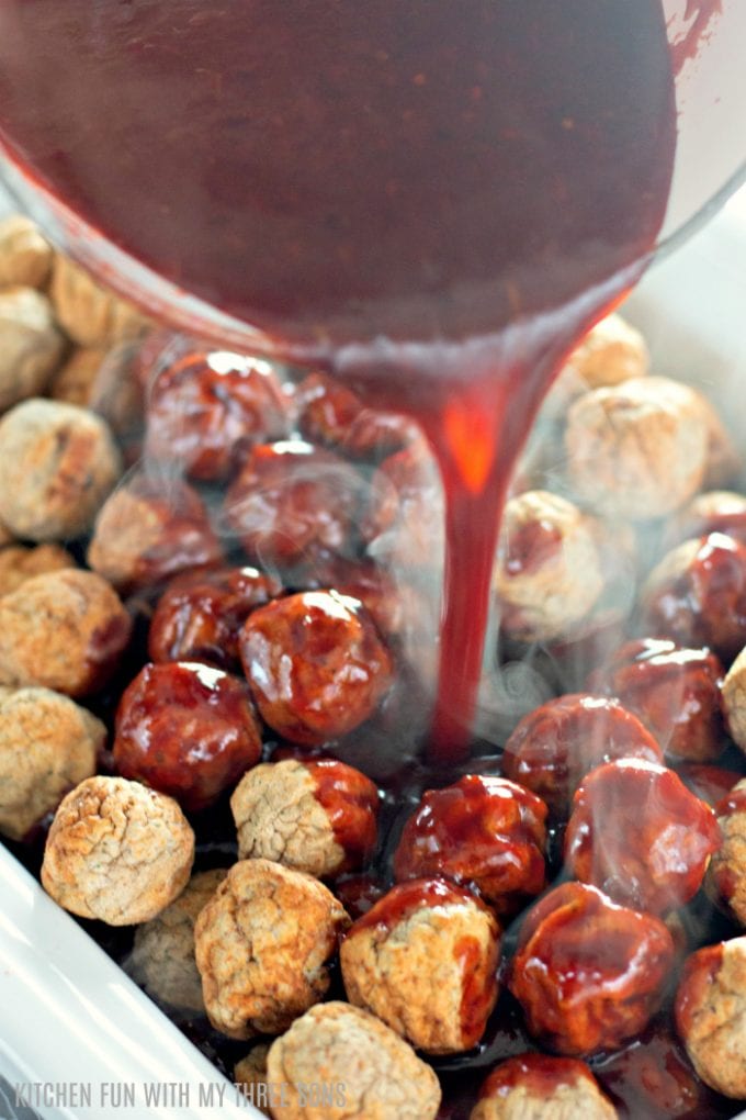 pouring sauce over frozen meatballs in a slow cooker
