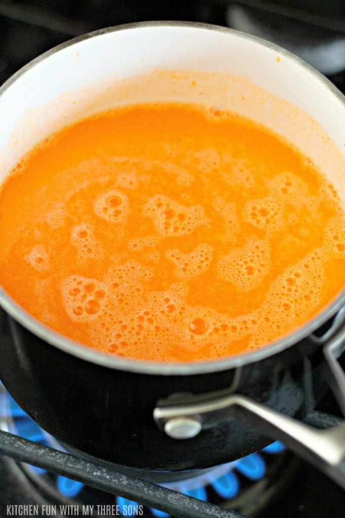 boiling orange Jello and water in a pot on a stove