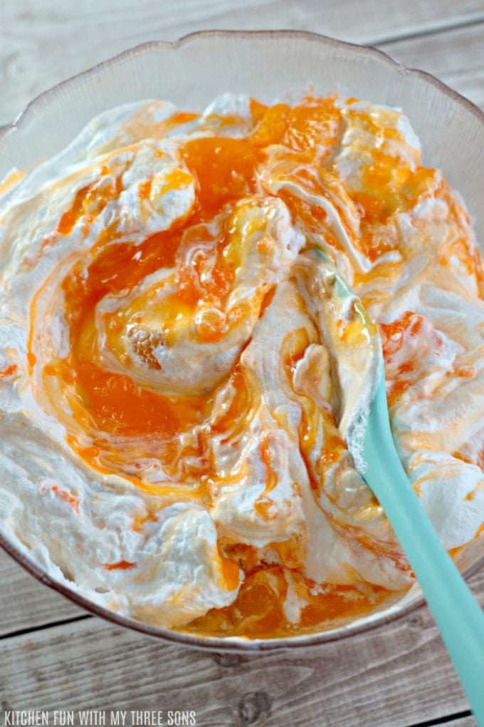 stirring together orange Jello and whipped topping