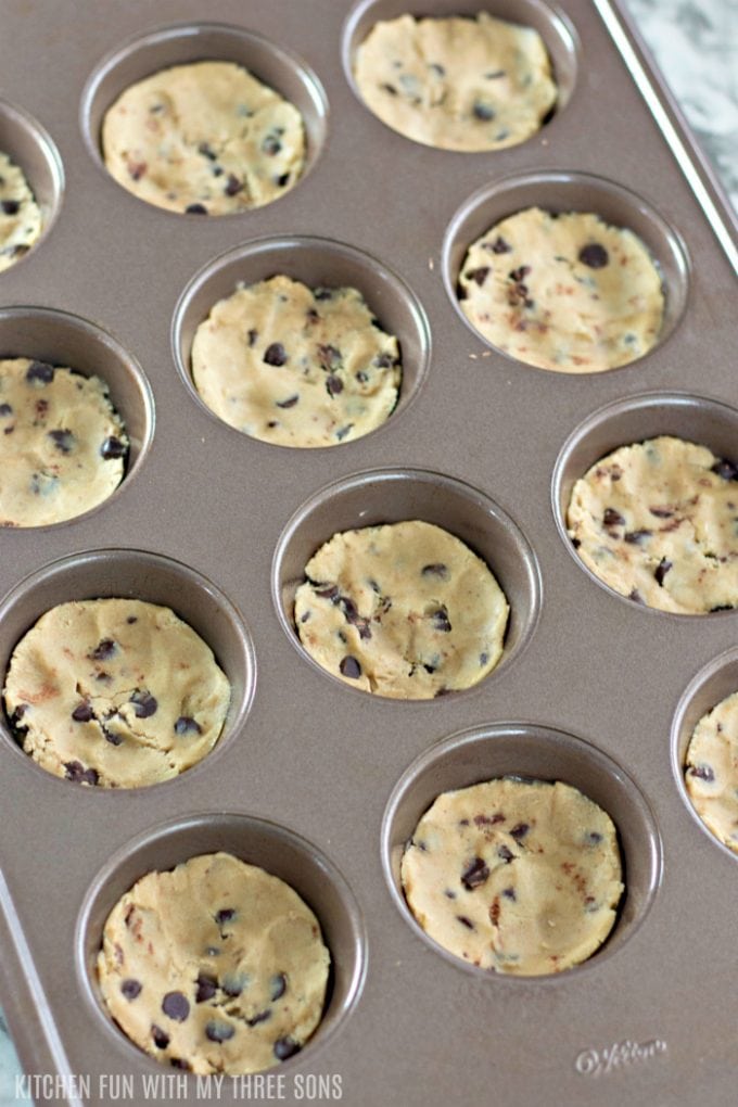 pressing chocolate chip cookie dough into a muffin pan