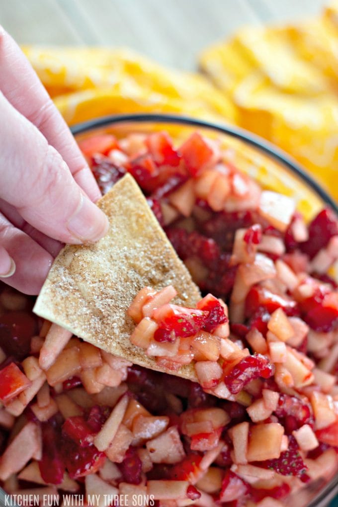 dipping a cinnamon sugar chip into a bowl of fruit salsa