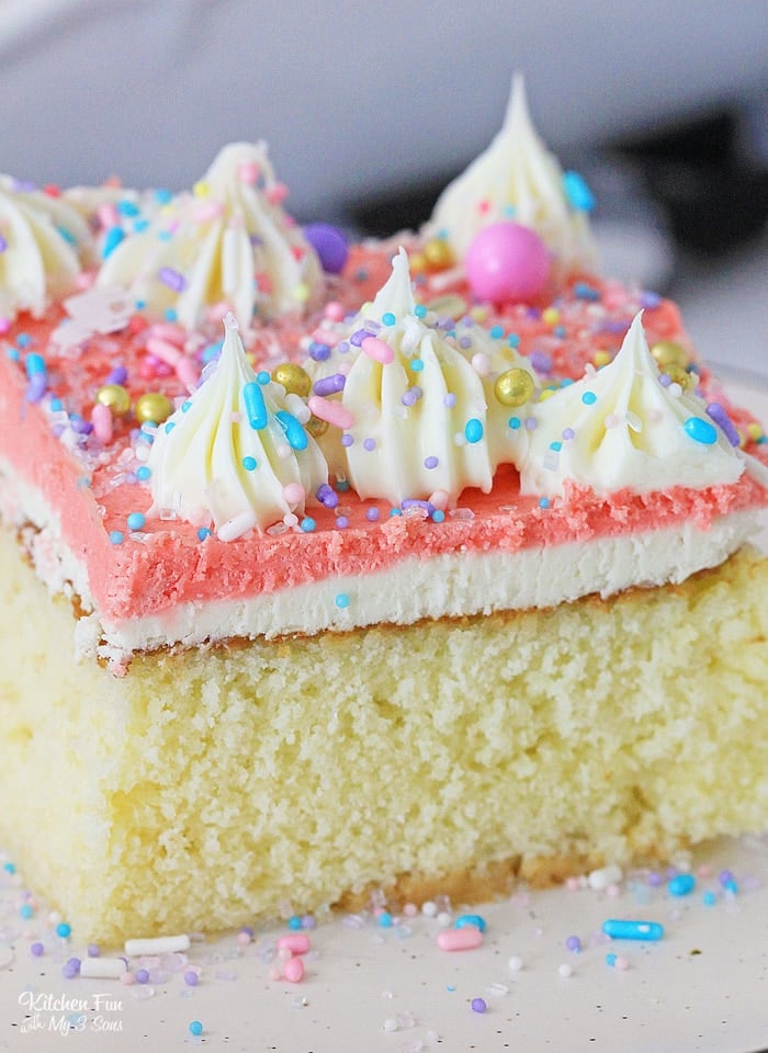 A slice of frosted Homemade Yellow Cake decorated with piped frosting swirls and rainbow sprinkles.