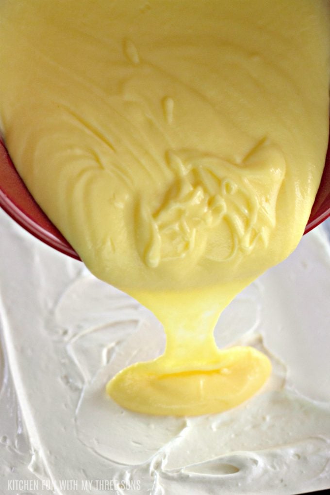 pouring vanilla and lemon pudding over cheesecake filling