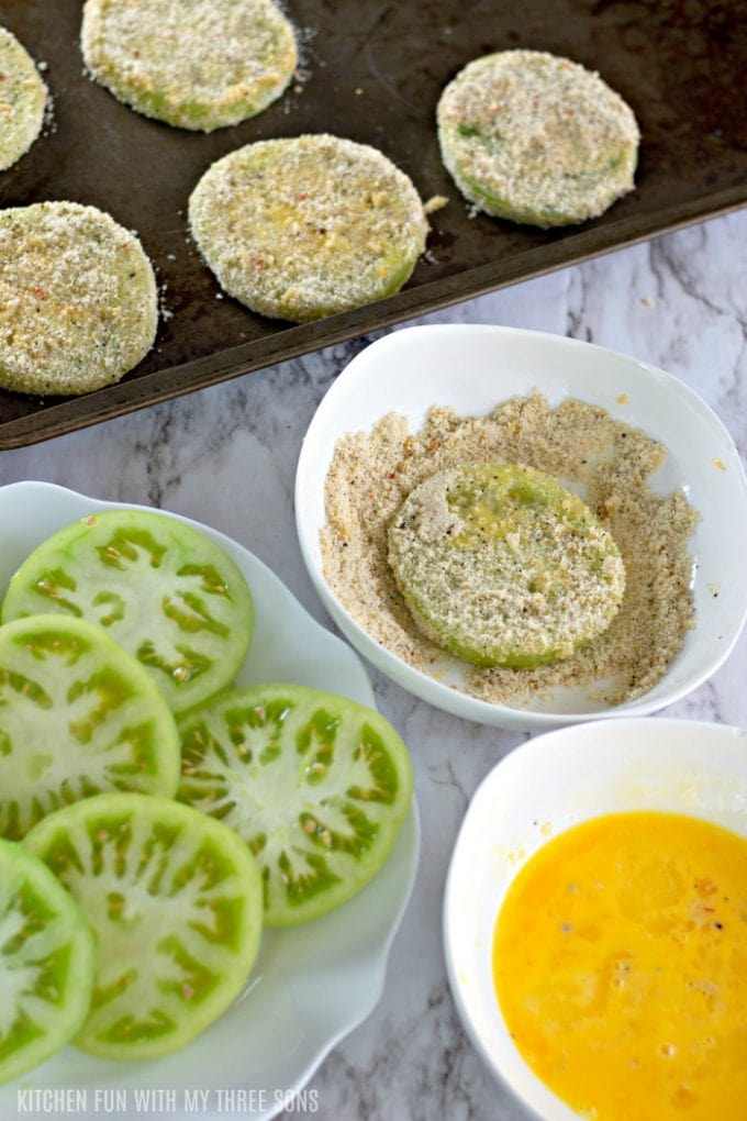 dredging green tomatoes in seasoned almond flour and egg