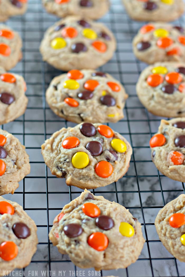 Rows of Reese's Pieces peanut butter cookies on a wire rack.