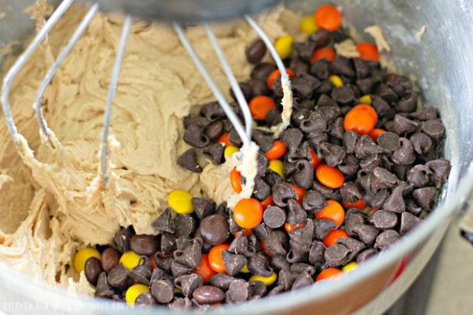 mixing chocolate chips and Reese's Pieces into cookie dough