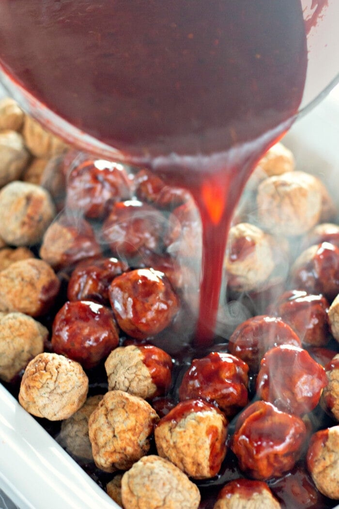 pouring sauce over the meatballs in a slow cooker