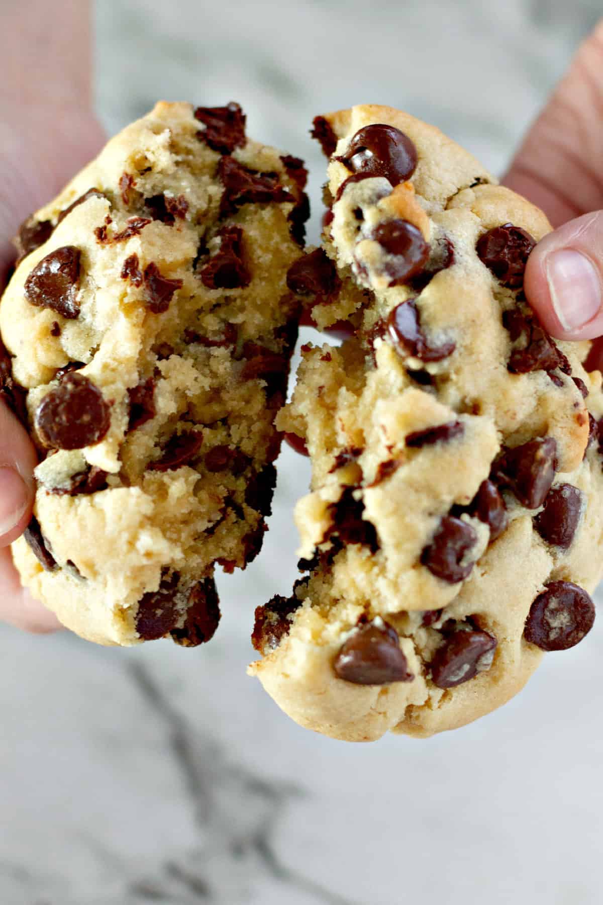 breaking a thick chocolate chip cookie in half