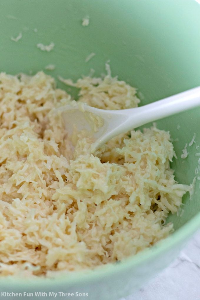 a mint green bowl filled with shredded coconut and sweetened condensed milk