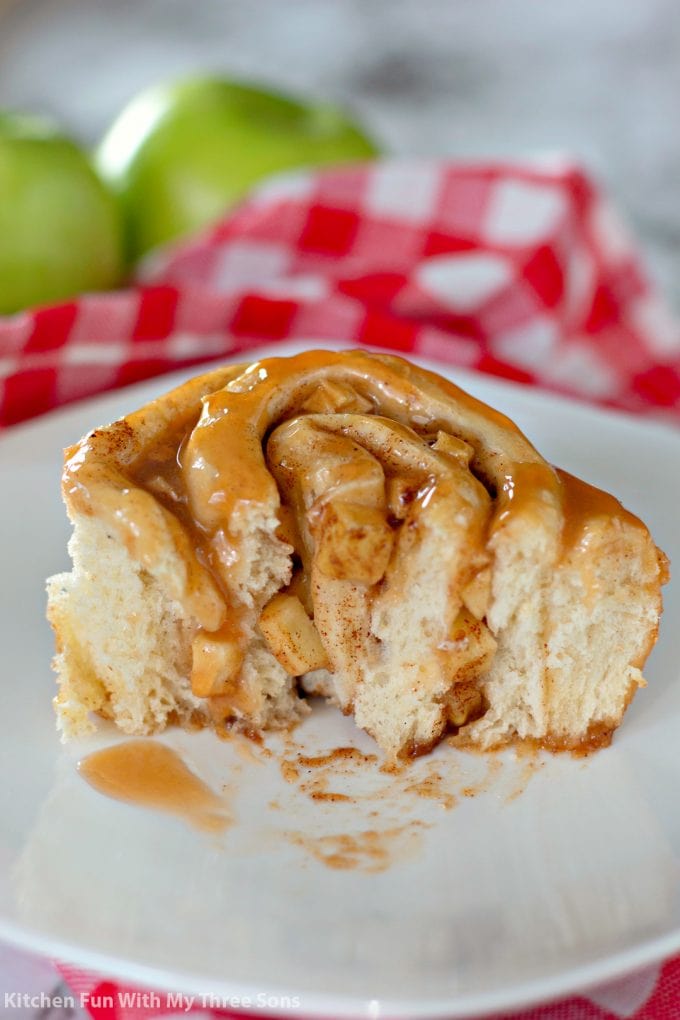 a Caramel Apple Cinnamon Roll cut in half and sitting on a white plate