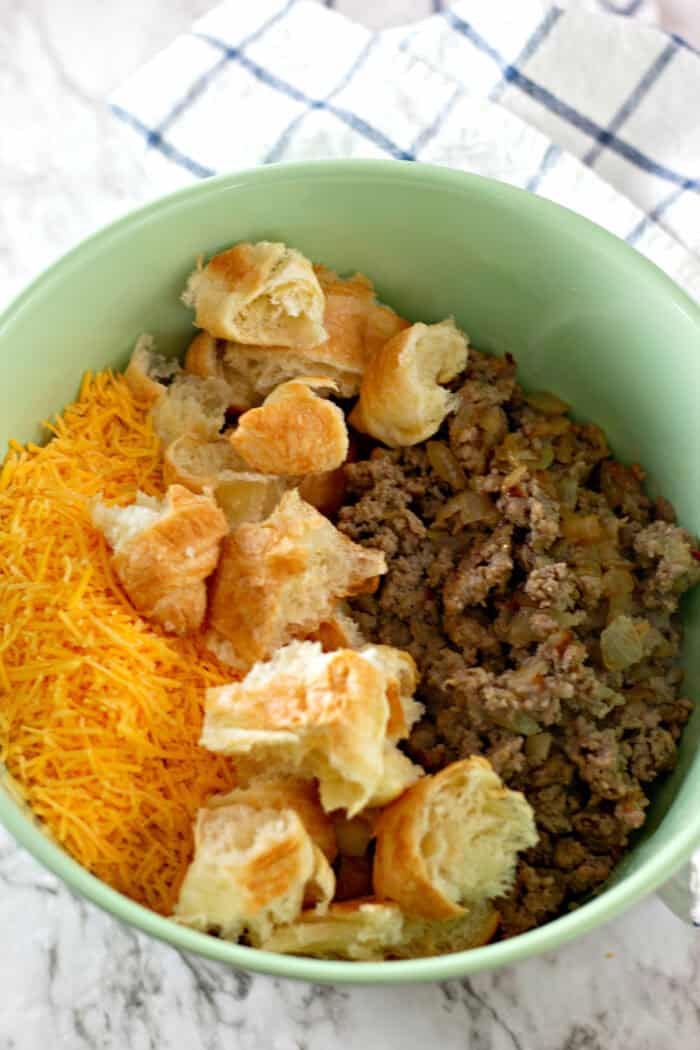 Shredded cheese, croissants, and sausage in a green bowl
