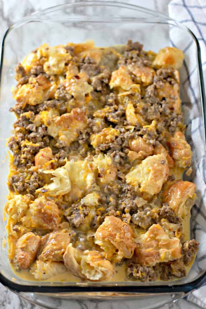 Overhead view of croissants, sausage, and eggs in a casserole dish