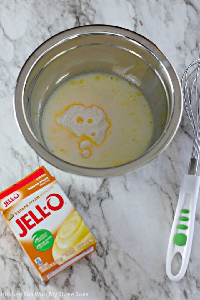 whisking together banana flavored Jello pudding with milk in a stainless steed bowl