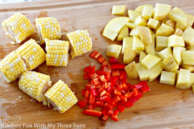 chopping potatoes, peppers, and corn on the cob