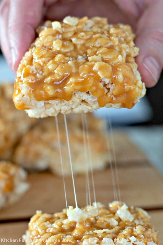 hand lifting a rice krispies treat with caramel