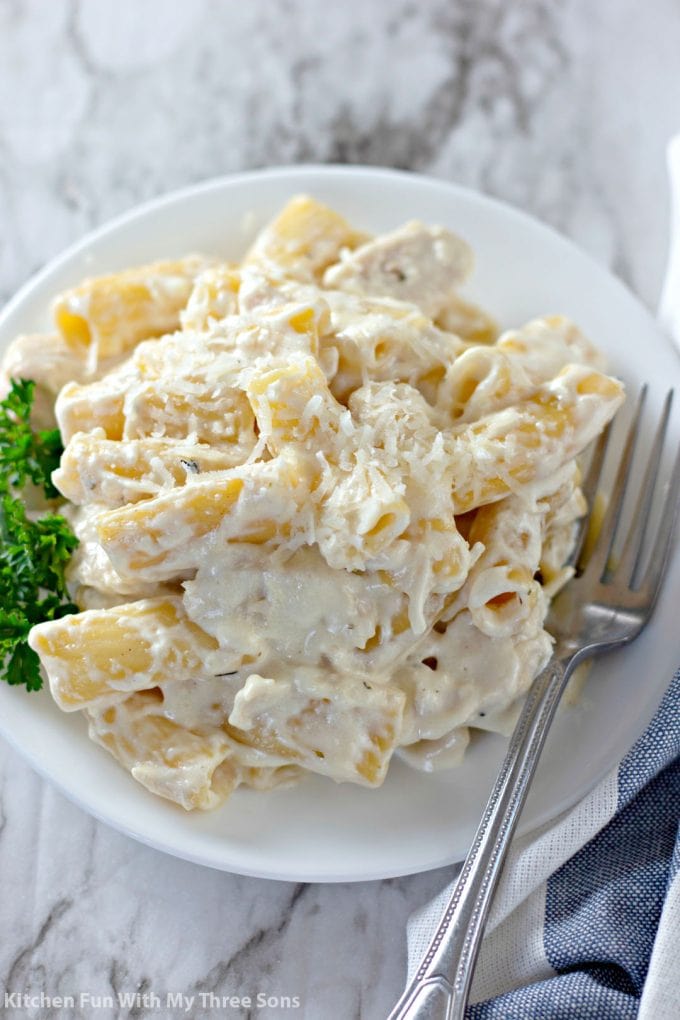 Slow Cooker Rigatoni Chicken Alfredo on a white plate with a fork