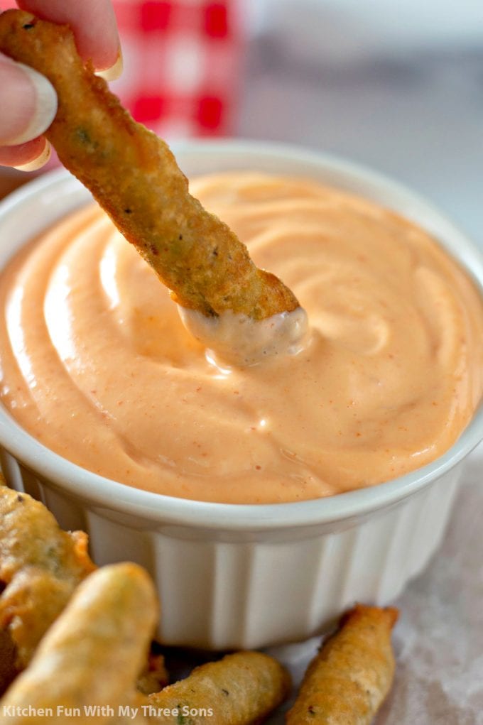 dipping Beer Battered Fried Green Beans in sriracha aioli