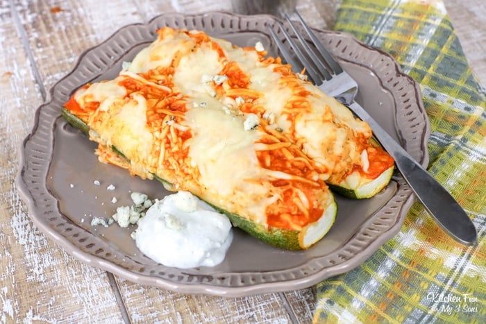 Two buffalo chicken zucchini boats on a plate next to a fork.