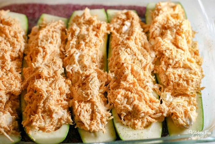 A row of unbaked zucchini halves stuffed with buffalo chicken mixture.