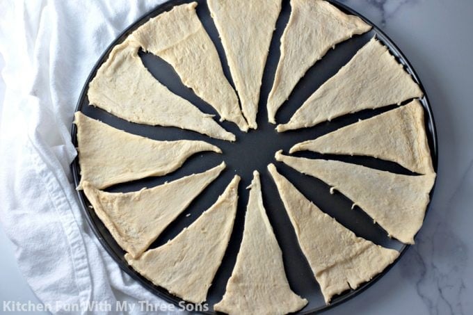 laying crescent rolls out on a pizza pan to form a circle