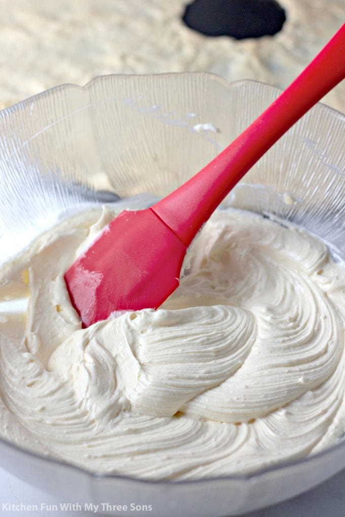 cream cheese filling in a clear bowl with a red spatula