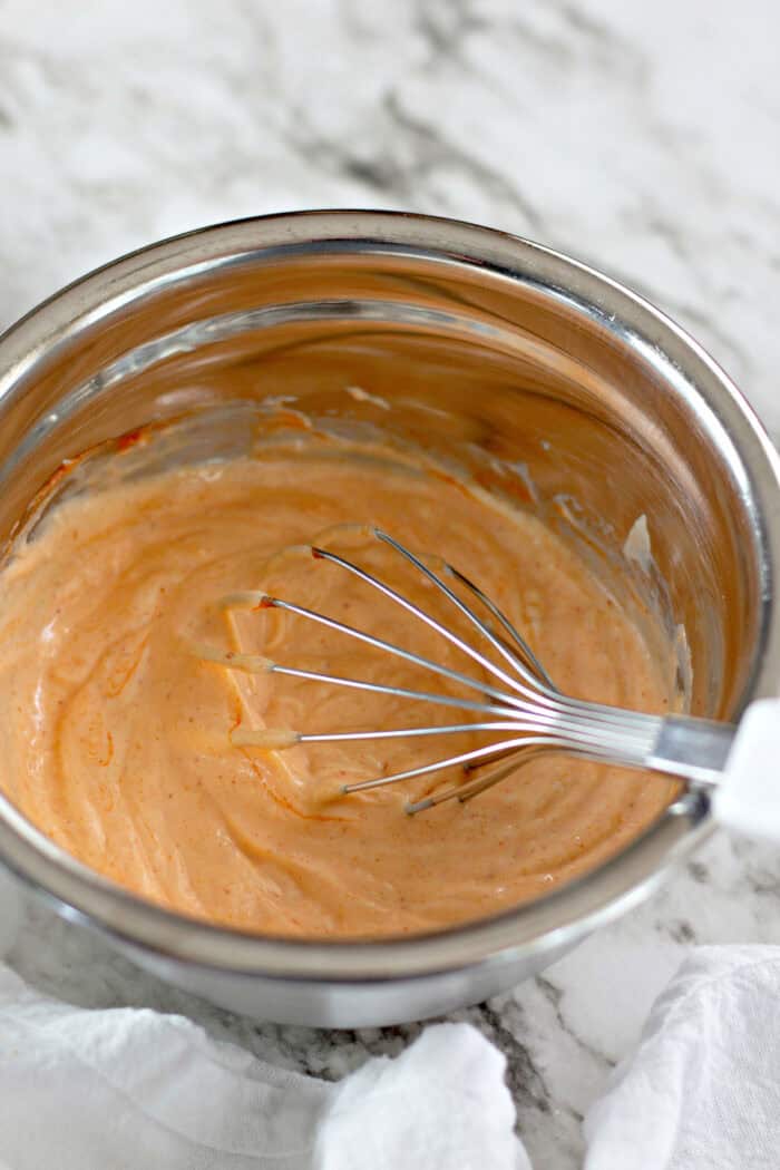 Whisking mayo and sriracha in a bowl