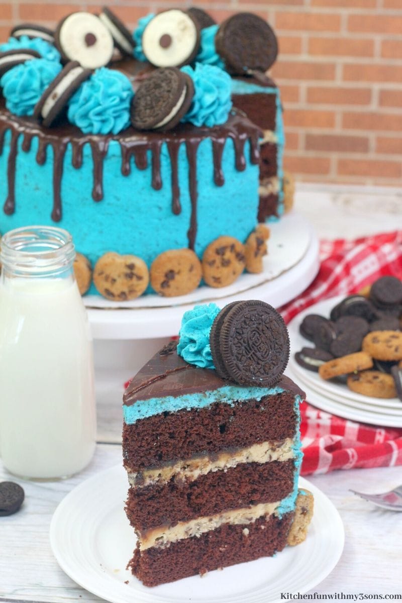 a slice of cookie monster cake on a plate with the full cake in the background