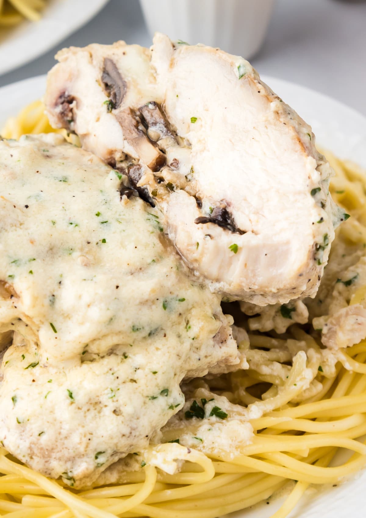 Stuffed chicken cut in half showing inside on a plate with noodles