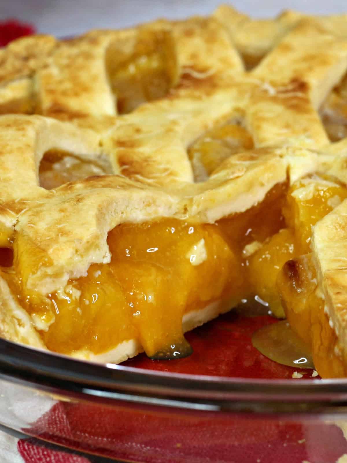 whole peach pie with a slice cut out