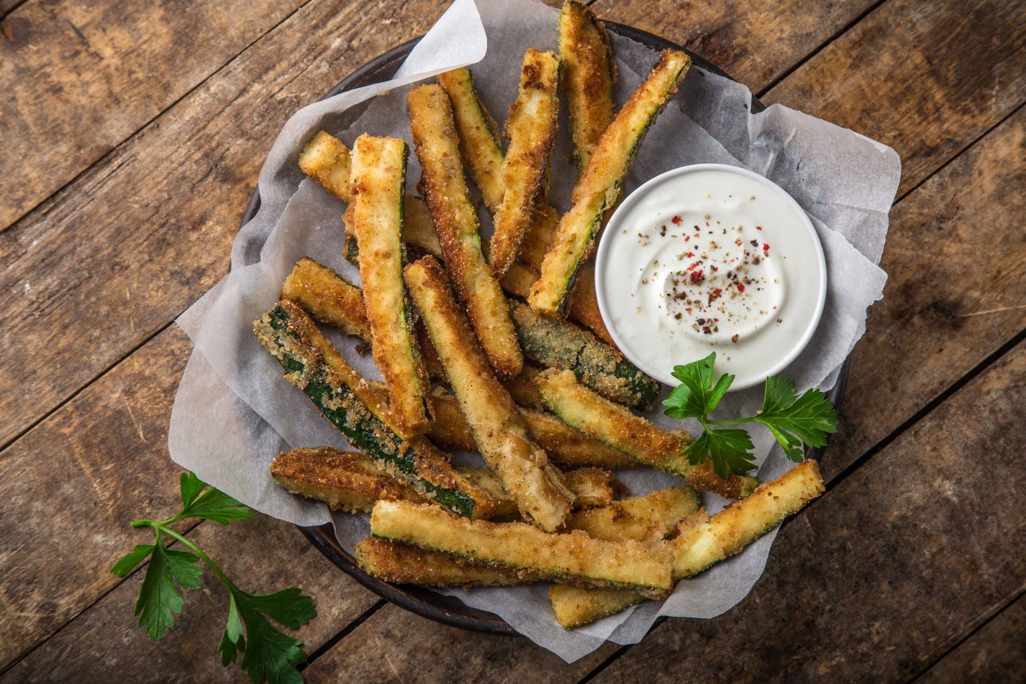 Overhead view of a plate of baked zucchini sticks with ranch dressing