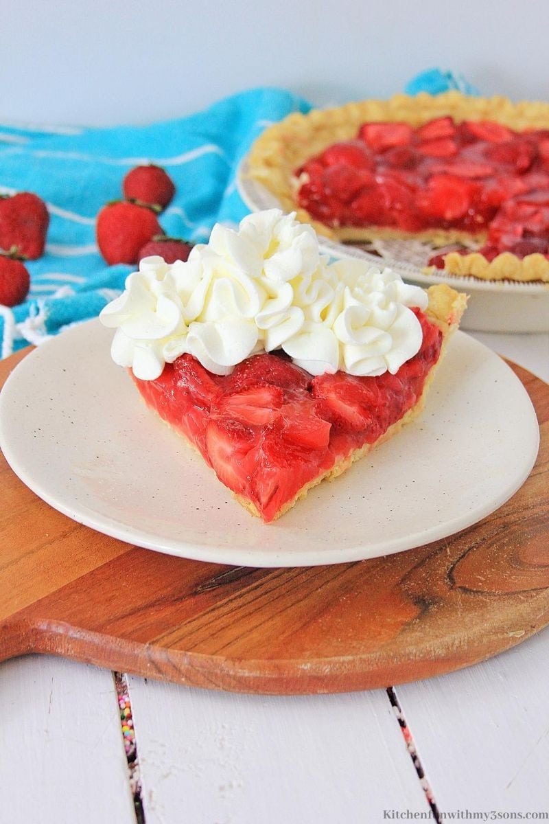 strawberry pie with whipped cream on a white plate