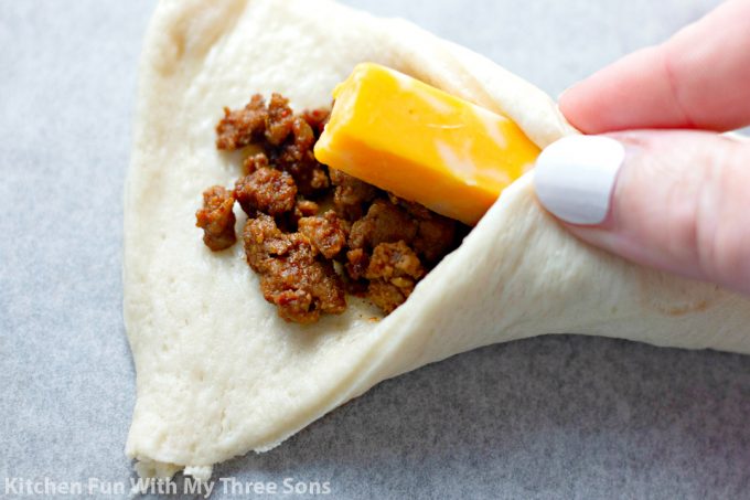 pinching pizza dough around taco meat and cheese to form a breadstick